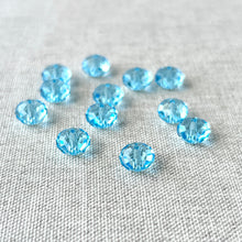 Load image into Gallery viewer, Scattered faceted 8mm Aquamarine Austrian Rondelle Crystals - Aquamarine Blue on a light textured fabric background, showcasing their bright blue color and sparkle.
