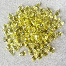 Load image into Gallery viewer, Scattered 15mm Jonquil CRYSTALLIZED™ Teardrop Drop Crystals in Jonquil Yellow with top drilled holes, displayed on a neutral fabric background, Package of 97.