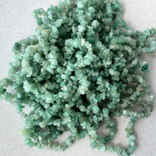Load image into Gallery viewer, Close-up of multiple strands of green aventurine - gemstone - chip beads with varying shades of soft green, arranged loosely on a light textured surface.