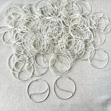 Load image into Gallery viewer, A large collection of Silver Plated Steel 50mm Round Hoop Earrings - 9 Closed Loops - Hinged - 50 pairs scattered on a light surface with two hoops prominently displayed in the foreground.
