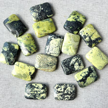 Load image into Gallery viewer, Yellow "turquoise" (natural), 25x18x7mm flat rectangle, B/C grade. Sold per 16-inch strand 16 Beads scattered on a light background showing their yellow and black mottled surface.