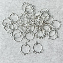 Load image into Gallery viewer, Pile of sterling silver circular chandelier drop components with six small loops each, shown against a light fabric background, for SS Circle Chandelier Drop - 19mm Round 6 Loops - Sterling Silver - Package of 22.