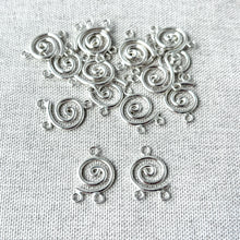Load image into Gallery viewer, Circle Spiral Chandelier Drop - 10mm Round 2 Loops - Sterling Silver - Package of 48, shiny silver spiral connectors for jewelry making with two attachment loops on textured fabric background.