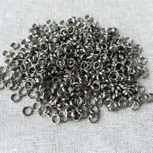 Load image into Gallery viewer, Close-up of a pile of silver-colored metal rings used for jewelry making, labeled as 5mm Rhodium Split Rings - Pack of 680 Splitrings, ideal for attaching charms and clasps.
