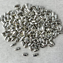 Load image into Gallery viewer, Close-up of multiple shiny silver diamond cut oval beads scattered on a light fabric background, Silver Diamond Cut Oval Beads - 7mm x 4mm - Pkg of 240 - Spacer Beads Metal Beads.