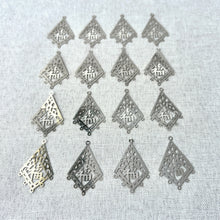 Load image into Gallery viewer, Drop, Lazer Lace™, silver-finished brass, 29x22mm kite with "Good luck" symbol with 5 loops - Sold per pkg of 16 arranged on a neutral fabric background.