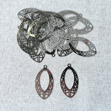 Load image into Gallery viewer, Drop, Lazer Lace™, silver-finished brass, 29x17mm fancy open marquise pieces arranged on a fabric surface, highlighting intricate geometric cutout patterns in a polished silver color.