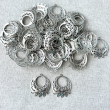 Load image into Gallery viewer, Filigree Circle - Domed Chandelier - White Plated over Brass - Silver - 30mmx24mm - Pack of 34 silver chandelier-style filigree jewelry components with intricate cut-out design on a light fabric background.