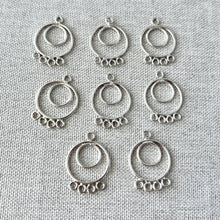 Load image into Gallery viewer, Circle Chandelier Drop - 15mm Round 4 Loops - Sterling Silver - Package of 8 jewelry components displayed on a textured fabric background, featuring double round loops and four smaller loops for attaching charms or chains.