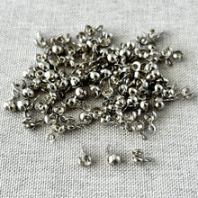 Load image into Gallery viewer, Bead Tip Clamshell Crimp Ends - Findings - Nickel Plated Brass - bead tip crimp beads with clamshells - Pack of 100, small shiny metal jewelry components on fabric surface.